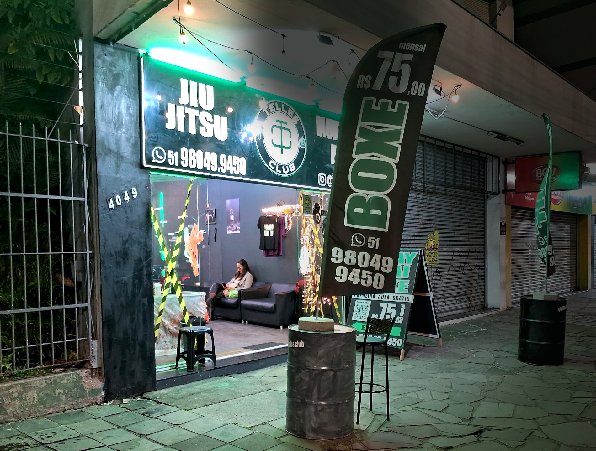 Fachada da Telles Club a noite na Av. Assis Brasil 4049, com letreiro em neon verde e o logo do clube